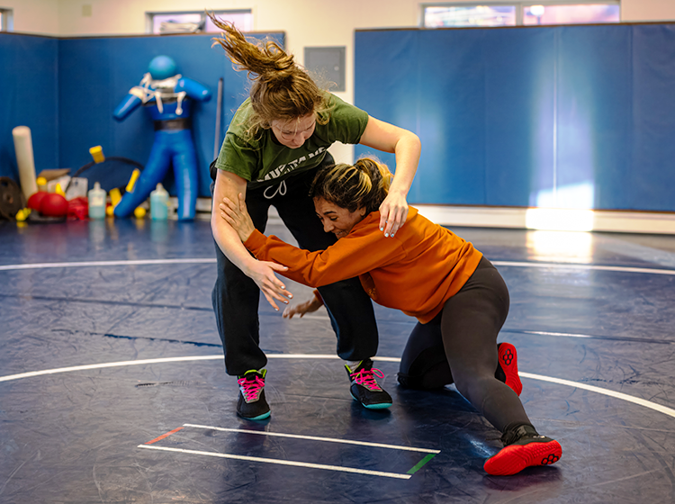 Two female wrestlers are practicing on the mats in the gym at Santa Rosa Junior College. 