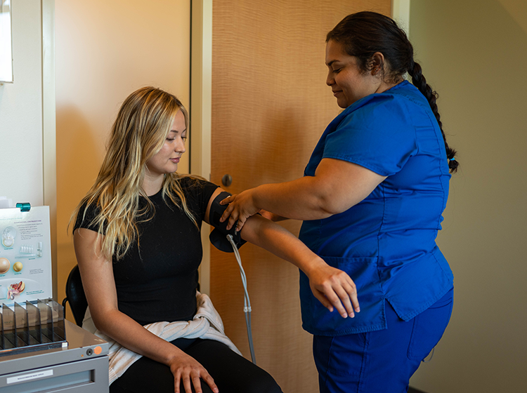 A young Latina female nurse takes the blood pressure of a young white female student at the Santa Rosa Junior College’s Student Health Services.