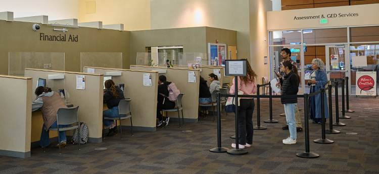 Multiple students stand in a cordoned line waiting to be assisted at the Financial Aid Office stations in Plover Hall at Santa Rosa Junior College.