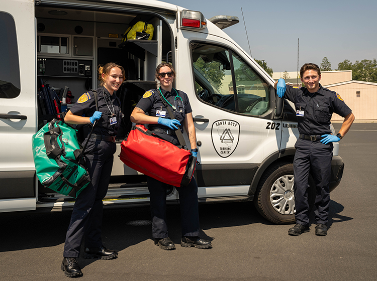 EMT students sanding in front of ambulance. 